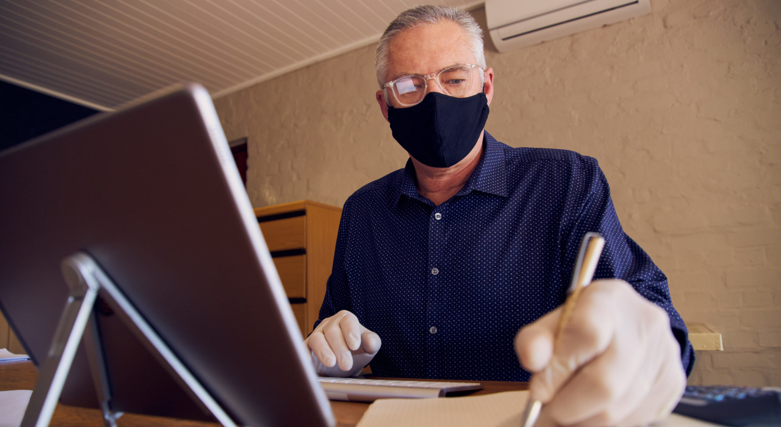 Businessman working at desk wearing a face mask